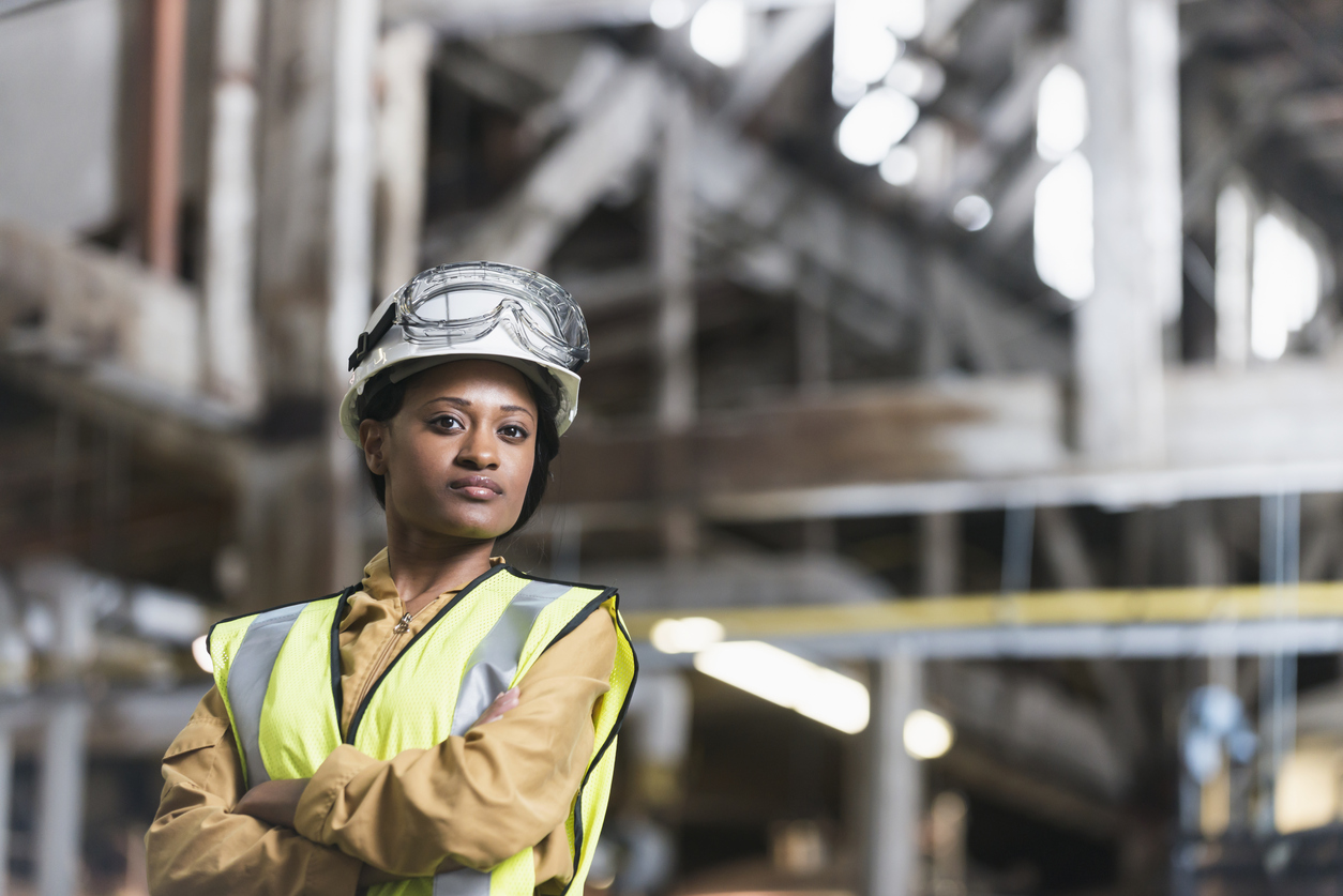 A woman in a hi-vis vest, hard hat and safety goggles standing in an industrial plant