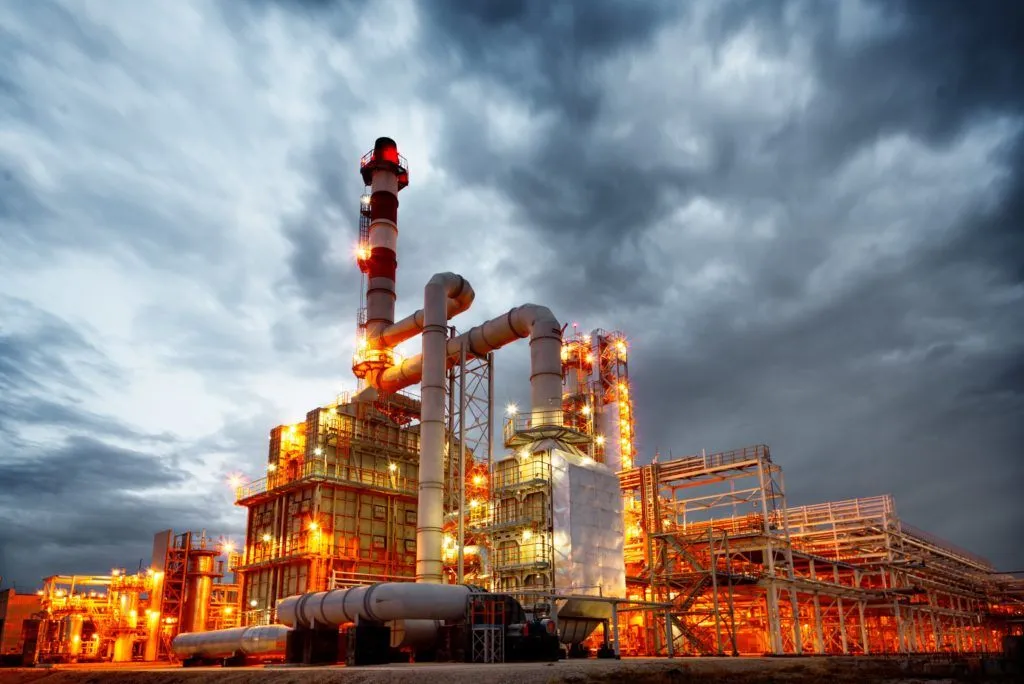 Oil refinery at dusk in extreme heat, the kind of prolonged heat exposure linked to dysautonomia