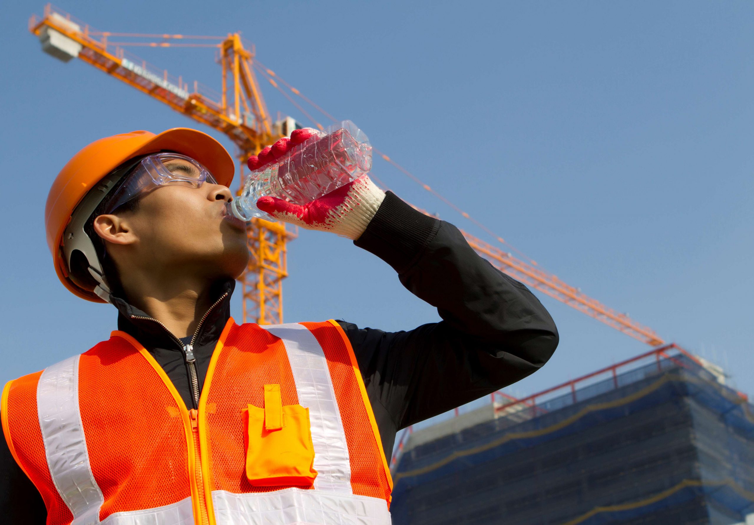 Worker drinking water at height on a job site in full sun