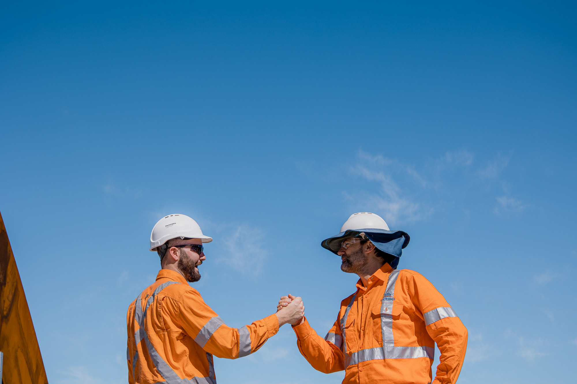 Two oil and gas workers in orange FR coveralls and hard hats